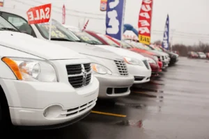 A row of used cars parked on a dealership lot with a prominent sale sign, showcasing the benefits of optimizing used car inventory management for a diverse customer base.
